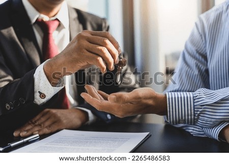 Real estate agent handing home keys to client after signing home purchase agreement. Signing real estate agreements, buying-selling, renting and mortgages.