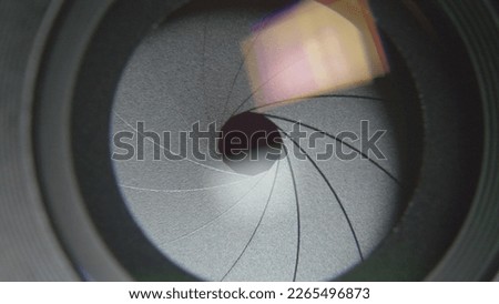 Front close-up view of camera lens diaphragm blades smoothly opening