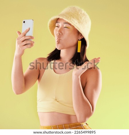 Selfie, beauty and Asian woman with funny face in studio isolated on yellow background. Comedy, crazy lips and comic female model taking pictures or photo for social media memory and profile picture