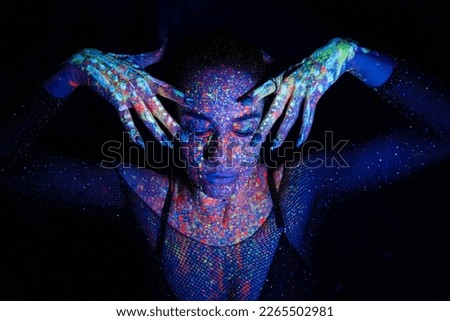Fashion model woman in neon light, portrait of a beautiful model with fluorescent makeup, artistic design of disco dancers posing in UV, colorful makeup. Isolated on black background