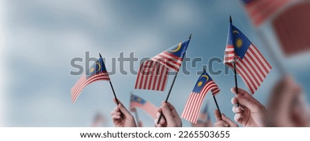 A group of people holding small flags of the Malaysia in their hands. Royalty-Free Stock Photo #2265503655