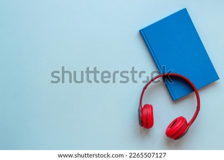 Book and headphones nearby. Lesten to audiobook or podcast concept