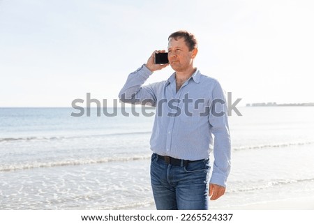 Businessman Talking On Phone, using smartphone mobile apps texting message, surfing social media tech standing on the city beach against the backdrop of the sea