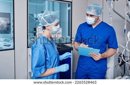 Nurses discussing notes with vital signs of patient in intensive care unit of hospital while working day