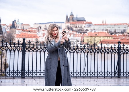A young female tourist in Prague takes a selfie photo to share online
