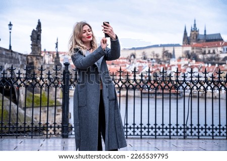 A young female tourist in Prague takes a selfie photo to share online
