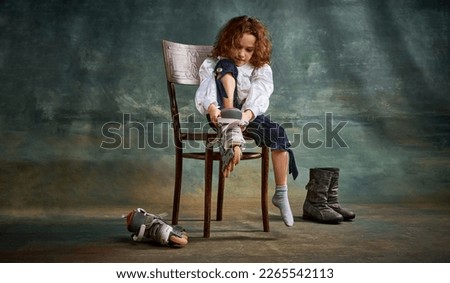 Full body portrait of positive little girl, kid learning to ride on roller skates isolated on dark background. Retro vintage fashion style concept. Model in image of medieval person