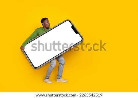 Photo of funny male carry large smart phone new model device black friday prices buyer isolated yellow color background