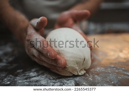 Close up view of hands shaping bread dough in artisan bakery