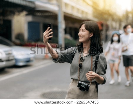 Young Asian woman backpack traveler using mobile phone, enjoying street cultural local place.
