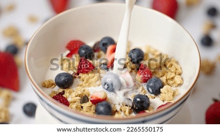 Milk pouring in bowl of healthy breakfast crunchy Granola Cereals with stawberry , blueberry vegan food, clean eating, dieting concept Royalty-Free Stock Photo #2265550175