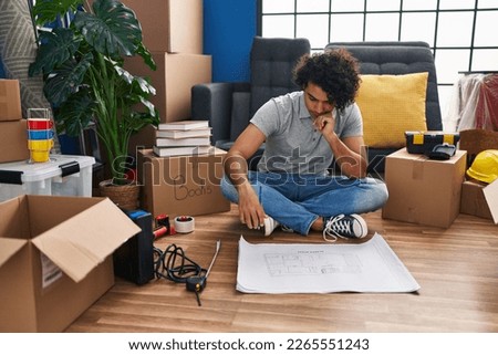 Young hispanic man having idea writing on house plan at new home