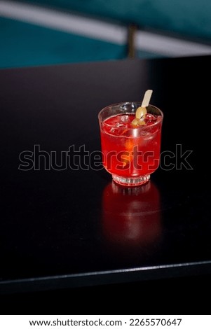 Cocktail red in hand on a dark background in the bar. Nightlife concept