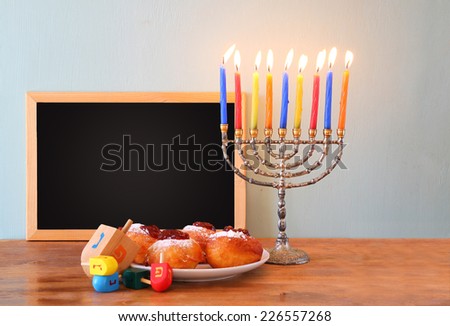 jewish holiday Hanukkah with menorah, doughnuts over wooden table. retro filtered image 