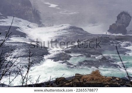 Scenic view of Rhine Falls with splashing water on a foggy winter day between Canton Zürich and Canton Schaffhausen. Photo taken February 16th, 2023, Laufen Uhwiesen, Switzerland.