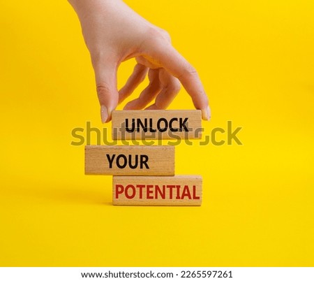 Unlock your Potential symbol. Wooden blocks with words Unlock your Potential. Beautiful yellow background. Businessman hand. Business and Unlock your Potential concept. Copy space. Royalty-Free Stock Photo #2265597261