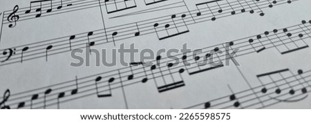 Music notes background. Musical concept background macro view of white score sheet music with notes with selective focus effect