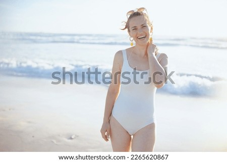 smiling stylish middle aged woman in white swimwear at the beach relaxing.