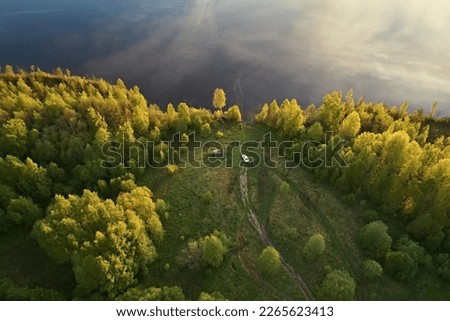 Top view of a clearing in the forest near the lake in the bright colors of the sunset. Beautiful abstract landscape from the air, photography with drone