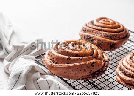 Sweet twisted buns with poppy seeds on cooling rack on white background with text space. Horisontal orientation