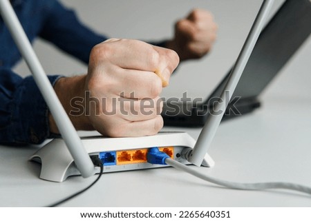 Frustrated young man angry at his wifi router modem at work. Royalty-Free Stock Photo #2265640351