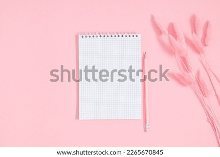 Empty notepad mockup, dry flowers, fluffy rabbit tail flower on pink background. Spiral open notebook on pink table. Flat lay, top view, copy space