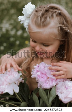 Beautiful little girl with big peonies bouquet. Spring blossom a