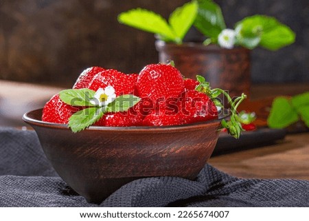 Strawberries in clay bowl on a wooden table. Bowl filled with juicy fresh ripe red strawberries. Selective focus