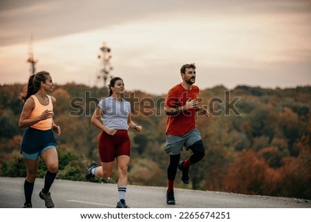 A small group of focused athletes enjoying running and communicating while jogging in nature. Royalty-Free Stock Photo #2265674251