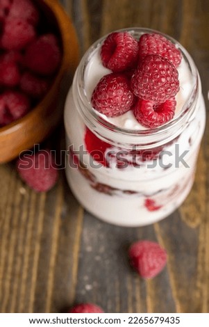 Fresh milk yogurt with whole fresh raspberries, a glass jar with raspberries and fresh yogurt from cow's milk