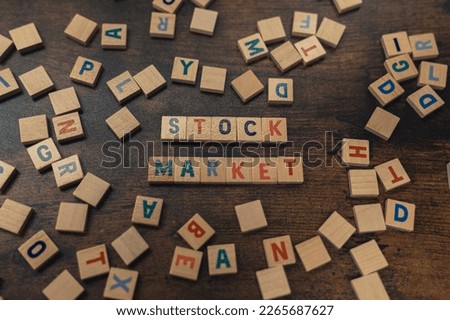 Stock Market spelled with Scrabble tiles on a wooden table with tiles scattered. High quality photo