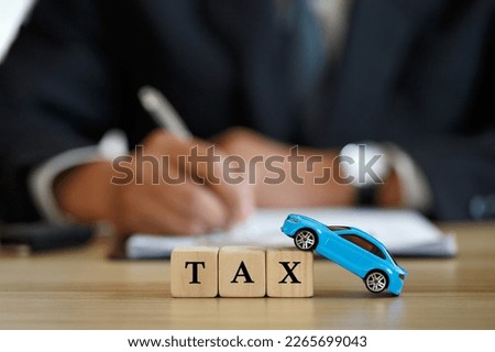 Car tax concept. close up tax wooden text with a toy car. saving money for transport, Man signing car insurance documents or lease papers. Writing signature on contract or agreement.