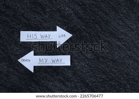 Handwritten words on paper arrows. God's way of life. Follow Jesus Christ. Biblical concept of godly wisdom, obedience, guidance, and Christian growth. Copy space, top view. Royalty-Free Stock Photo #2265706477