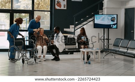 Male doctor consulting old woman with cardiac pressure, feeling heartburn in hospital waiting room. Patient with heart problems and cardiovascular disease receiving consultation at health center. Royalty-Free Stock Photo #2265724423