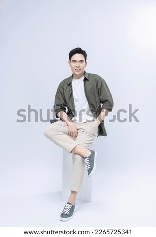 Young Asian man sitting on background Royalty-Free Stock Photo #2265725341