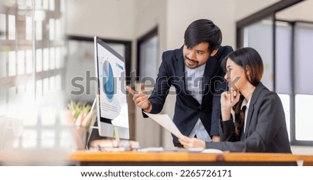 Team of confident Asian business people point to graphs and charts to analyze market data, balance sheet, account, net profit to plan new sales strategies to increase production capacity. Royalty-Free Stock Photo #2265726171