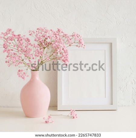 Frame mockup with copy space for artwork, photo, painting, print presentation and pink  modern vase with pink flowers near white wall .Minimal scandinavian interior design.