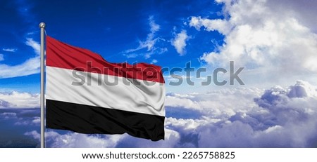 Yemen national flag cloth fabric waving on beautiful blue sky.