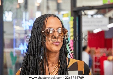 An African American woman with long sisterlocks wearing a brown and black dress, sunglasses in a coffee shop at the Municipal Market in Atlanta Georgia USA Royalty-Free Stock Photo #2265766769