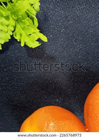 Black background photo for creative industry. photos of tomatoes and green leaves on a black cloth