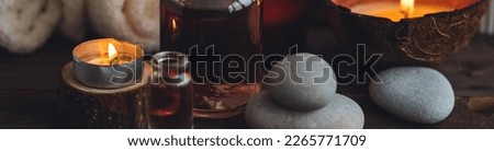 Concept of natural essential organic oils, Bali spa, beauty treatment, relax time. Atmosphere of relaxation, pleasure. Candles, towels, dark wooden background. Alternative oriental medicine. Banner Royalty-Free Stock Photo #2265771709