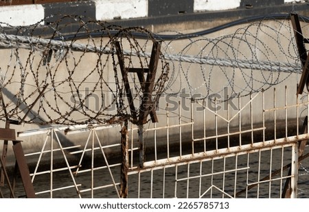 Restricted area. Passage is prohibited closed. Border from old barbed metal barrier wire. Concept of border, prison, war, military base, refugees. Selective focus. As a conceptual modern background