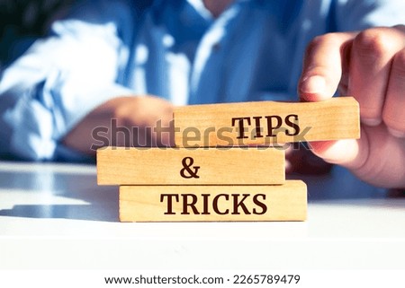 Close up on businessman holding a wooden block with "TIPS AND TRICKS" message