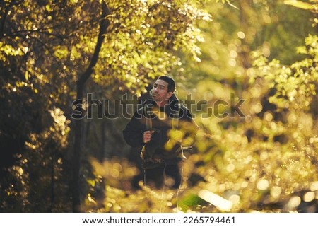 Man, backpacker and hiking in nature forest, trekking woods or trees for adventure, relax workout or fitness exercise. Japanese hiker, walking and person in environment, healthcare or cardio wellness Royalty-Free Stock Photo #2265794461