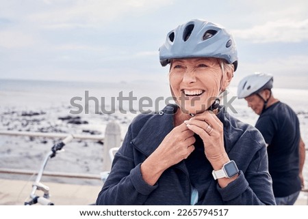 Happy senior woman, bicycle and helmet on holiday ride at beach for fitness workout with man. Smile on face, happiness and health, cycling exercise for mature couple on ocean vacation in Australia. Royalty-Free Stock Photo #2265794517
