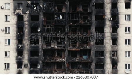 A burnt-out high-rise in the war zone. Damage to a residential building as a result of artillery shelling. War in residential areas, broken windows and burned apartments. Armed conflict in Ukraine Royalty-Free Stock Photo #2265807037