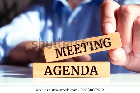 Close up on businessman holding a wooden block with Meeting agenda message, business concept