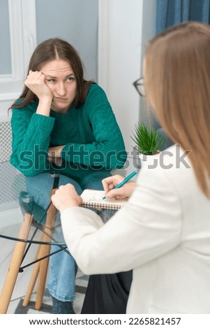 Young woman attentively and emotionally listens to a psychologist at the reception. Consultation of a psychologist in a modern office. Concept of psychological health. Vertical photo