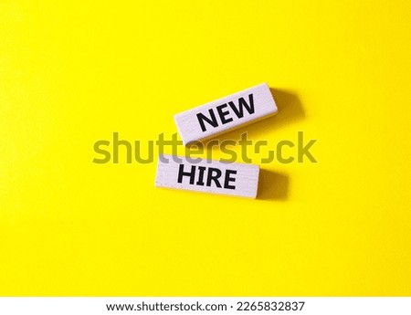 New hire symbol. Wooden blocks with words New hire. Beautiful yellow background. Business and New hire concept. Copy space.