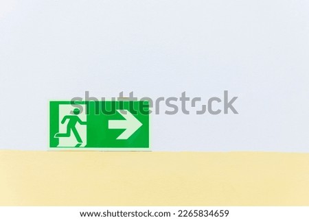 Emergency exit symbol on the hospital wall to inform escape route from fire alarm in an emergency condition. Sign of exit way in the green background with copy space. Hospital or factory use symbol.